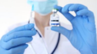 Yüz maskesi olan doktorlar hastanede şırınga ve Aşı Ampulü tutuyor. Yeni İlaç Geliştirme, Aşı, Önleme. Biontech, Şırıngada Moderna.