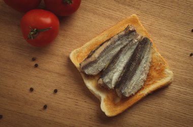 Canned sardines on toasted slice of bread clipart