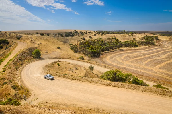 Car driving up hill on curvy rural dirt road — Stock Photo, Image