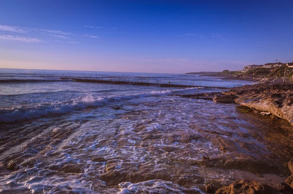 Salida del sol en la playa rocosa en la Australia urbana — Foto de Stock