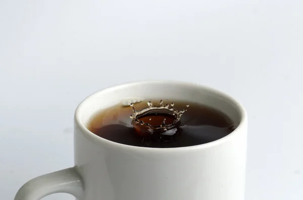 Cup of tea with water splash on white background