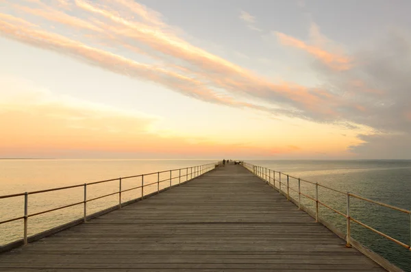 Embarcadero de madera al atardecer con nubes en el cielo — Foto de Stock