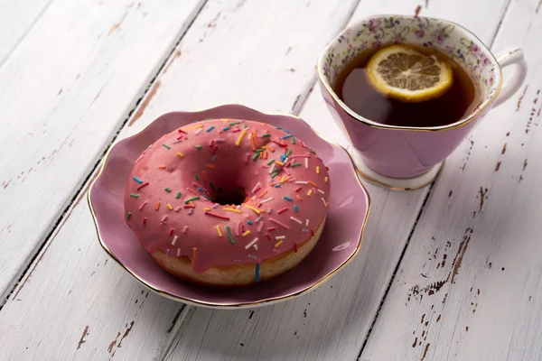 Розовый пончик и лимонный чай на белом столе — стоковое фото