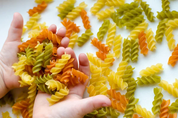 Child hands full of spiral pasta — Stock Photo, Image