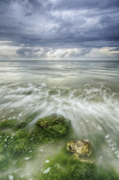 Piccola onda che colpisce la pietra. white.beautiful onda bianca scorrono sopra le alghe e roccia sulla spiaggia — Foto Stock