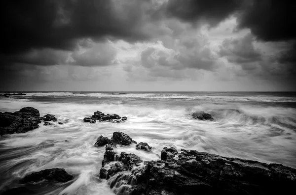 Onda de imagen en blanco y negro golpeando la costa con una nube dramática — Foto de Stock