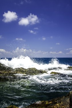 bulutlu ve mavi gökyüzü arka plan ile kıyı kayaya isabet dalga yumuşak