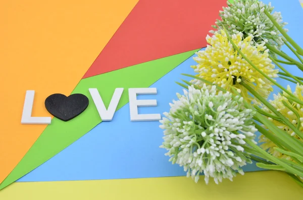 Романтический взгляд со словом любовь и символика. Три искусственных круга желтый, зеленый и белый цветок на цветном фоне — стоковое фото