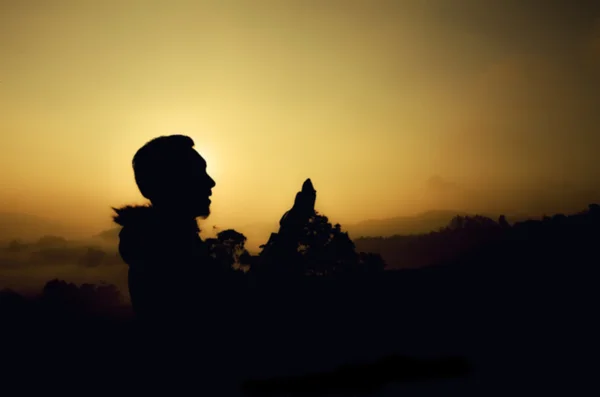 Unschärfe Bild Silhouette eines Mannes stehend und beten. dunkler und körniger Hintergrund. Sonnenuntergang und Sonnenaufgang — Stockfoto