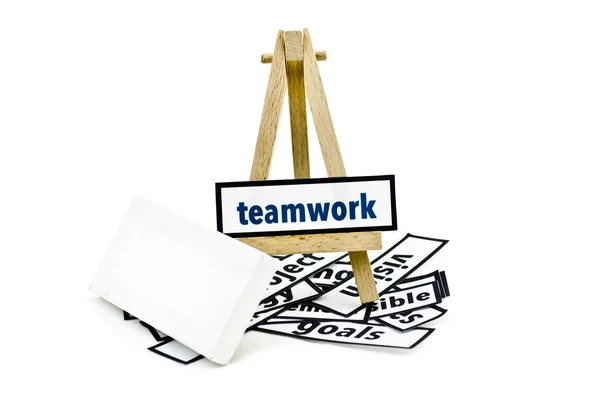 Concept teamwork word on wooden stand.random cutted print paper and empty canvas frame isolated white background — Stockfoto