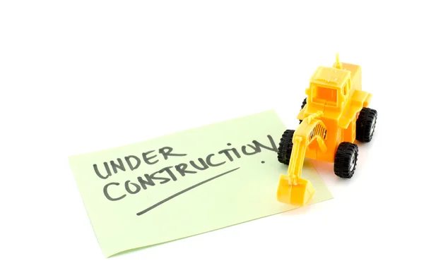 Bulldozer amarillo con la palabra borrosa en construcción escribió en papel verde — Foto de Stock