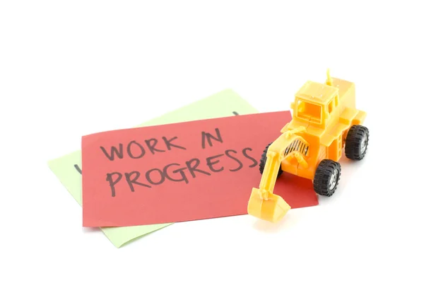 Image concept yellow toy bulldozer on red paper and blur word work in progress — Stock Photo, Image