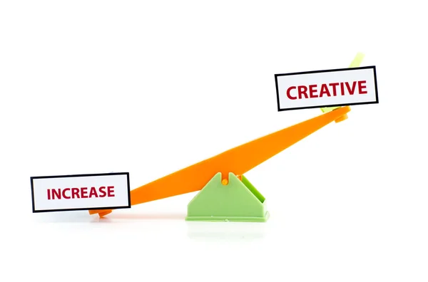 Image concept of unbalance word INCREASE at bottom and CREATIVE on top.green and orange color toy seesaw — ストック写真