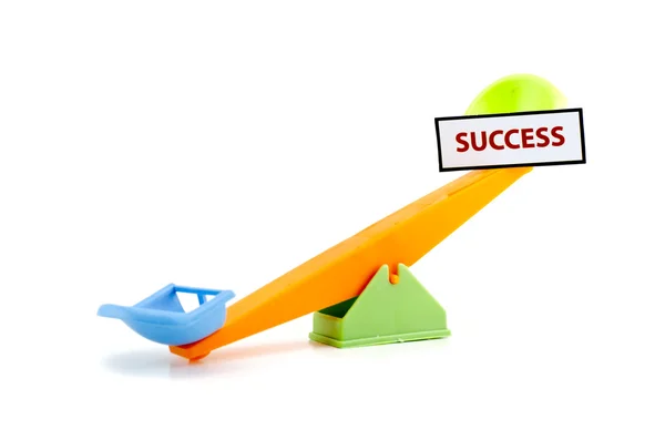 Image concept unbalance seesaw with word SUCCESS printed with red ink on white paper attach to the seesaw — Stockfoto