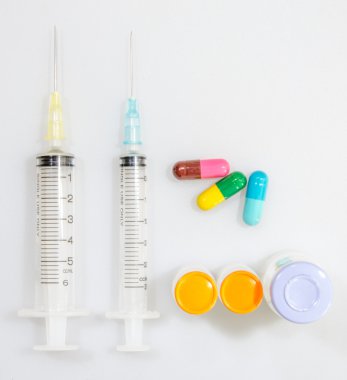 Beyaz arka plan üzerinde şırınga ve tablet ilaç