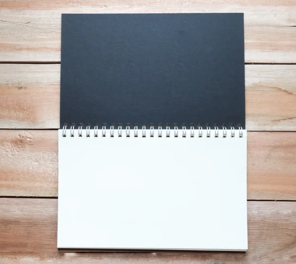 O caderno preto com anel de metal e piso de madeira — Fotografia de Stock