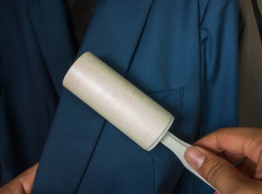 Kuru Temizleme ve iş Tema: Mavi takım elbise ve mobilya toz temizlik için beyaz bir yapışkan fırça tutan adam yardım