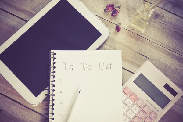 To do list notebook with tablet calculator pencil on wood floor , digital effect vintage style