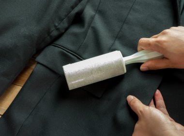 Kuru Temizleme ve iş Tema: siyah takım elbise ve mobilya toz temizlik için beyaz bir yapışkan fırça tutan adam yardım