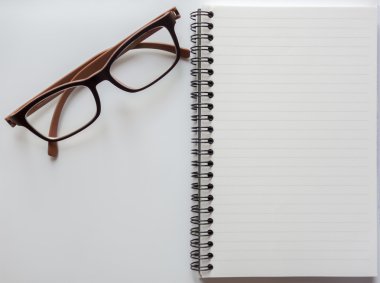 Boş defter gözlük ile Üstten Görünüm alanı olan beyaz arka plan üzerinde