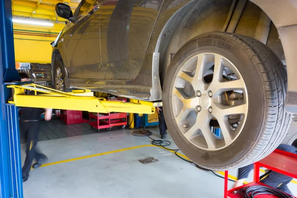 Подъем автомобиля для ремонта в гараже — стоковое фото