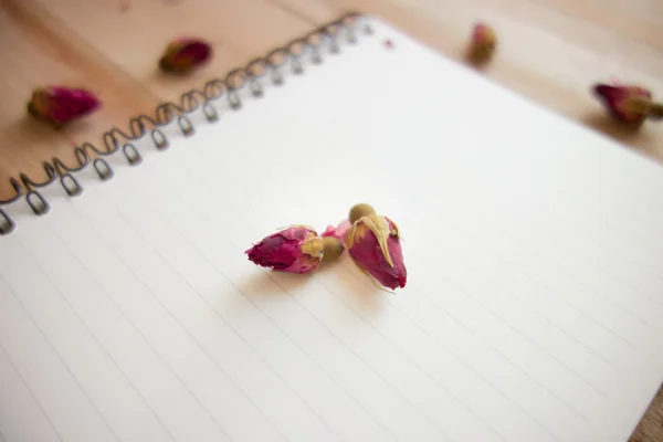 Caderno em branco com espaço de cópia e rosa colocada no chão de madeira — Fotografia de Stock