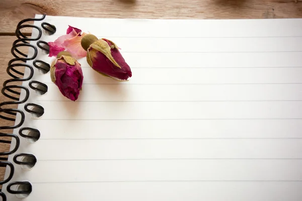 Caderno em branco com espaço de cópia e rosa colocada no chão de madeira — Fotografia de Stock