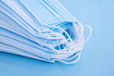 Koronavirüsü önle. Covid için birkaç tıbbi maske. Mavi arka planda bir sürü tıbbi koruyucu maske var..