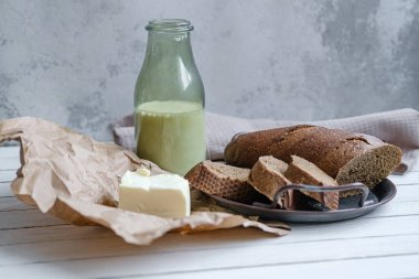 Doğal bir tahta üzerinde süt ve tereyağlı dilimlenmiş ekmek. Kırsal biçim.