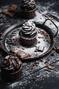 Birkaç kek ya da siyah masada çikolata şekilli kremalı kekler. Pudra şekeri keklerin üzerine saçılmış..