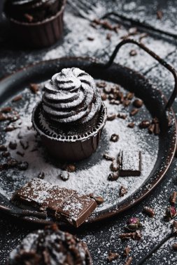 Birkaç kek ya da siyah masada çikolata şekilli kremalı kekler. Pudra şekeri keklerin üzerine saçılmış..