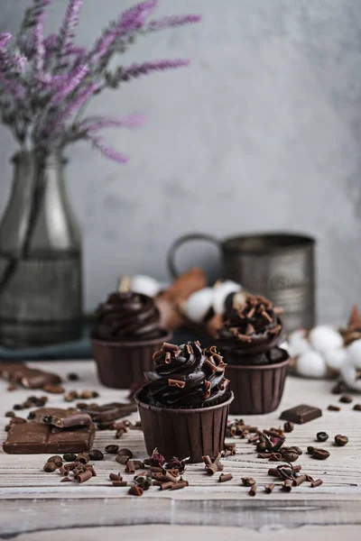 Varios panecillos o cupcakes con crema en forma de chocolate en la mesa blanca. Vela festiva quema en un pastel de chocolate. Imagen de archivo