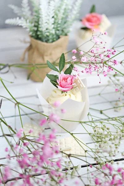 Beyaz tereyağı kremalı birkaç kek ve beyaz ahşap bir masada pembe bir gül. Sevgililer Günü ya da Anneler Günü hediyesi. Kırsal biçim.