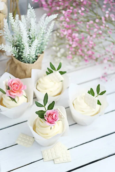 Vários cupcakes e muffins com creme de manteiga branca e uma rosa animada subiram em uma mesa de madeira branca. Dia dos Namorados ou presente do Dia das Mães. Estilo rústico. — Fotografia de Stock