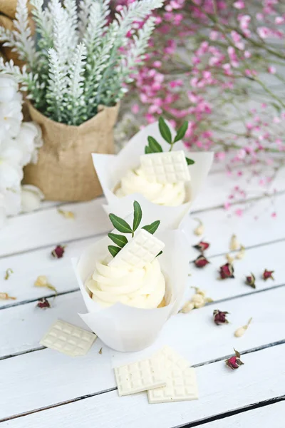 Beyaz ahşap bir masada beyaz tereyağlı kremalı birkaç kek ve kek. Sevgililer Günü ya da Anneler Günü hediyesi. Kırsal biçim.