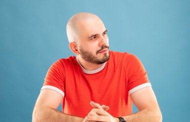 Mavi arka planda kırmızı tişörtlü, sakallı orta yaşlı bir adam kollarını açıp zafere seviniyor. İzole edilmiş.