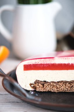 Turuncu dolgulu kırmızı ve beyaz pasta. Siyah bir masanın üzerinde portakallar ve fındıklar var. Kırsal biçim.