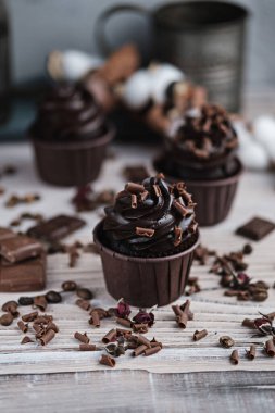 Beyaz masada çikolata şekilli kremalı birkaç kek ya da kek. Kutlama mumu çikolatalı pastada yanar. Yakınlarda çikolata parçaları var..