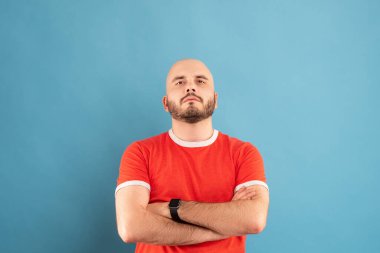 Mavi arka planda kırmızı tişörtlü, sakallı orta yaşlı bir adam kollarını açıp zafere seviniyor. İzole edilmiş.