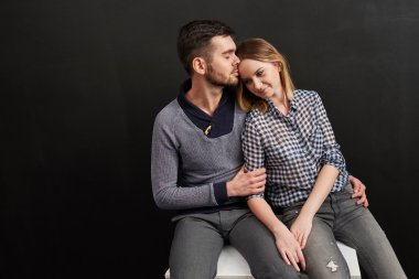 Beautiful couple sitting against of black background