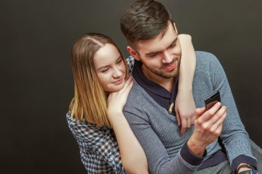 Young bearded man sitting next to his girlfriend while using sma