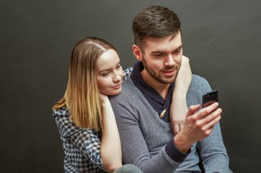 Young bearded man sitting next to his girlfriend while using sma
