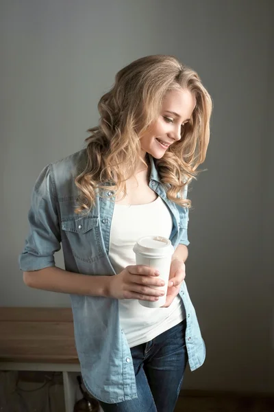Lovely woman with wavy hair holding a cup of  coffee
