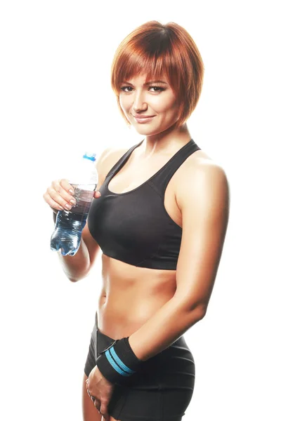 Young fit woman standing and looking at camera with bottle of wa — ストック写真