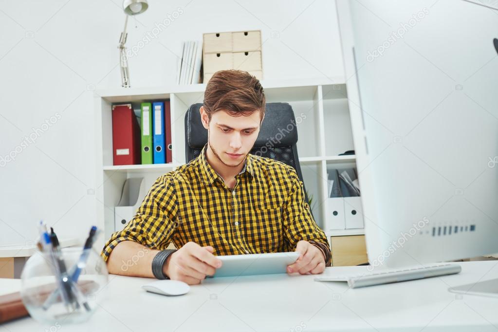 the young man behind the desk in the office working on the table