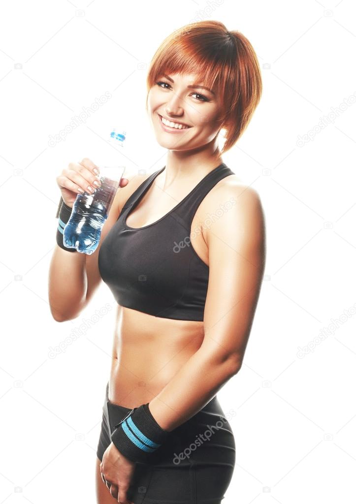 Young fit woman standing and looking at camera with bottle of wa