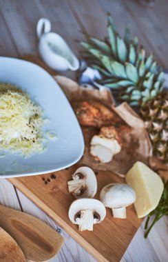 Makarna ve pizza yapmak için malzemeler. Mantar, et, ananas, sos, peynir, tahta masanın üzerine tereyağı. Rustik.