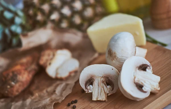 Ingredients for making pasta and pizza. Mushrooms, meat, pineapple, sauce, cheese, butter on the wooden table. Rustic.
