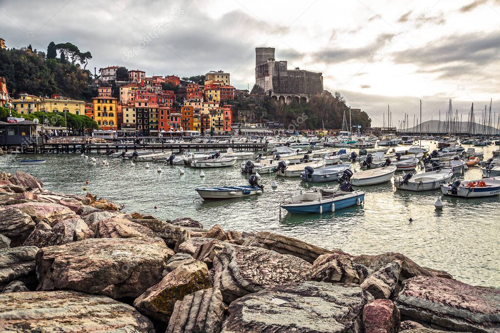 Unique seascape view of an italian village on Mediterranean sea with touristic harbor, colored houses and Lerici castle in the background before sunset, La Spezia, Liguria, Italy