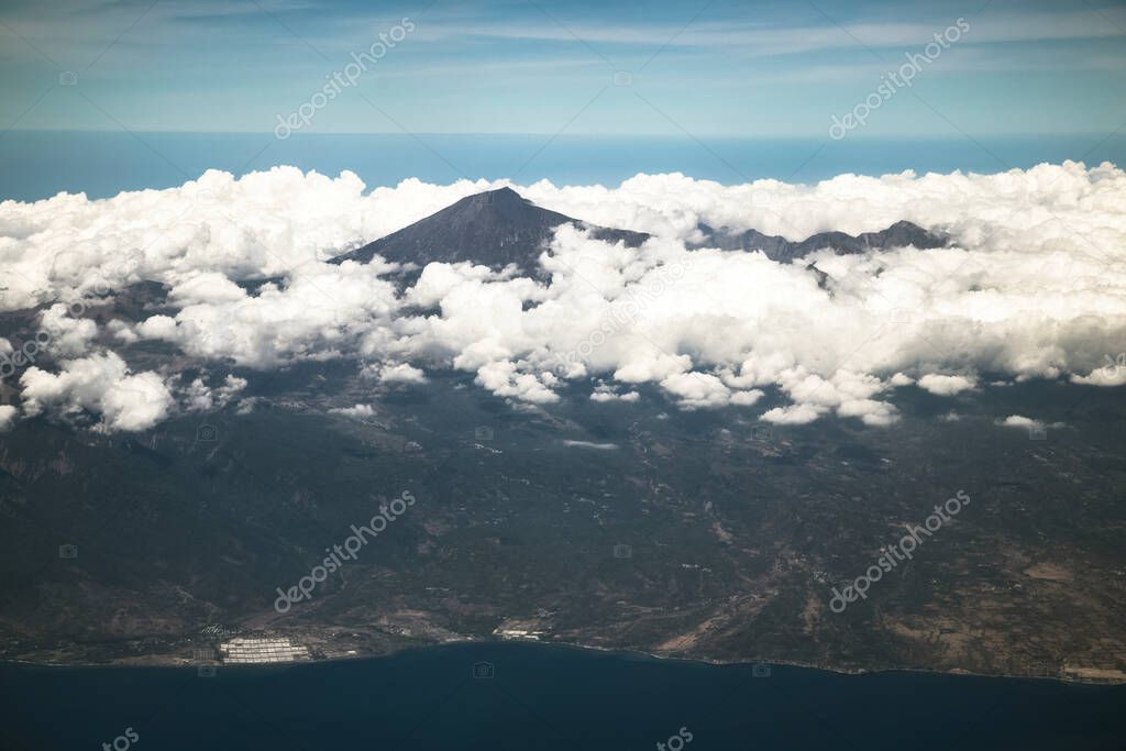 Aerial view of tropical active volcano surrounded by clouds, Ring of fire, Indonesia